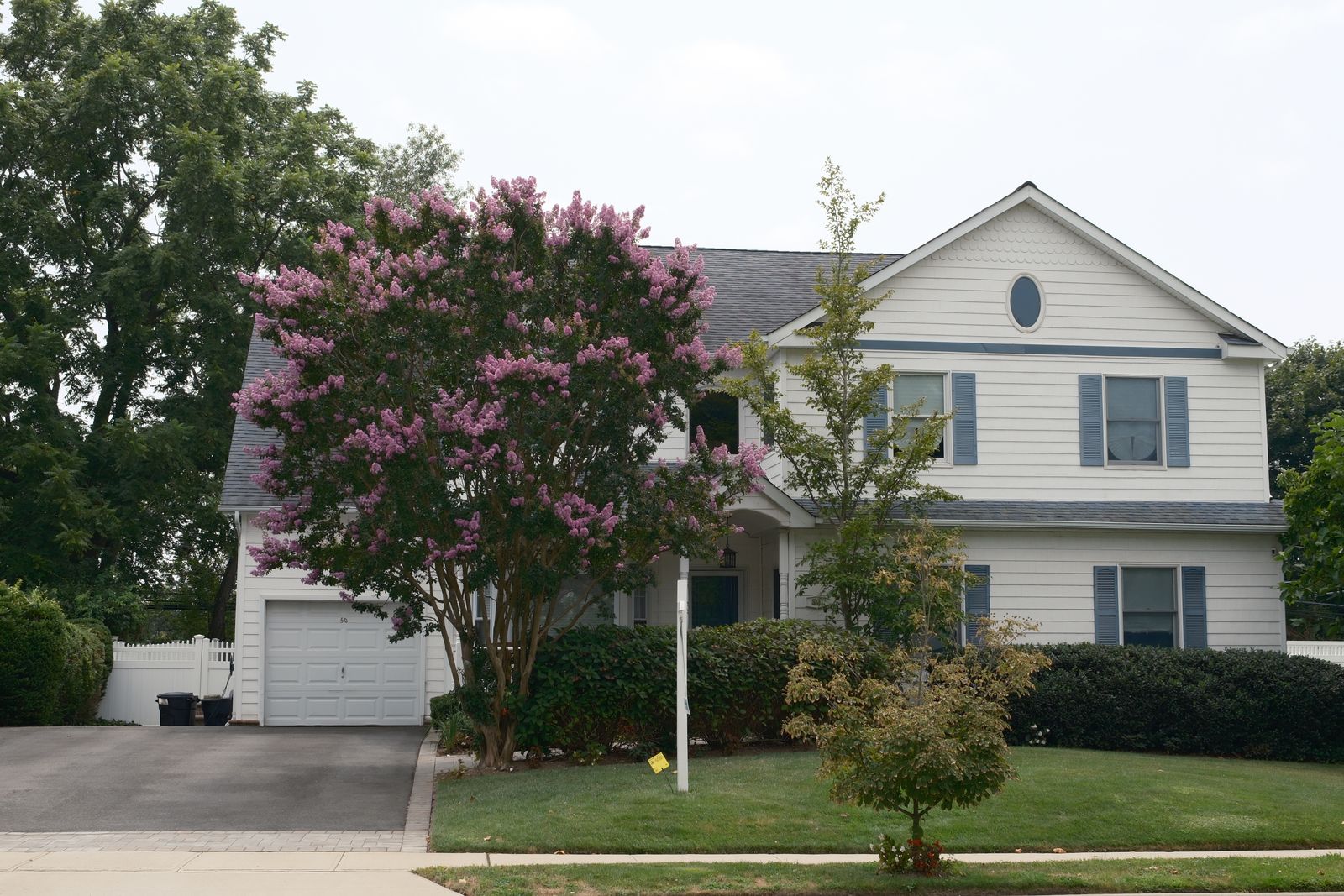 Asphalt driveway beside a landscaped home yard