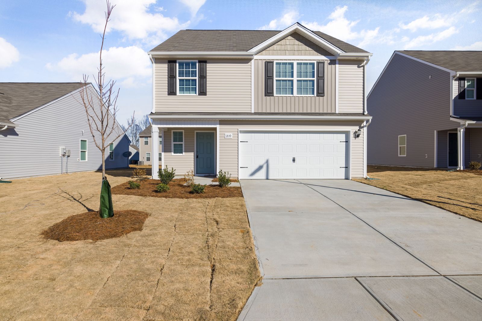 Light concrete driveway leading to a private home's garage